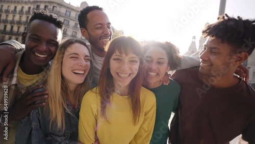 Travel with happy friends. Young smiling people looking at camera hugging. Group of multicultural boys and girls having fun outdoors celebrating vacations Erasmus together in Europe. Modern lifestyle.