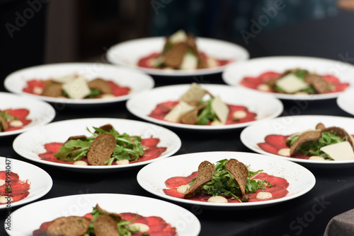 white dish with carpaccio of beef. the chef is preparing to serve a meal in a restaurant