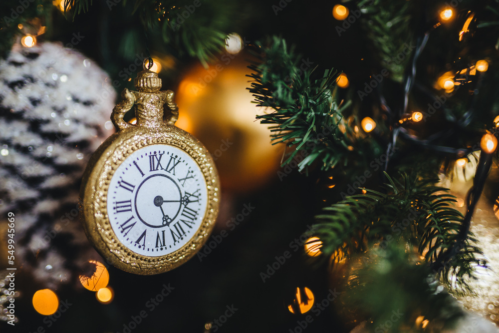 Picture of decorated New Year or Christmas tree with garlands and baubles. Decoration in form of clock symbolizes starting new year. Holidays, celebration, winter concept.