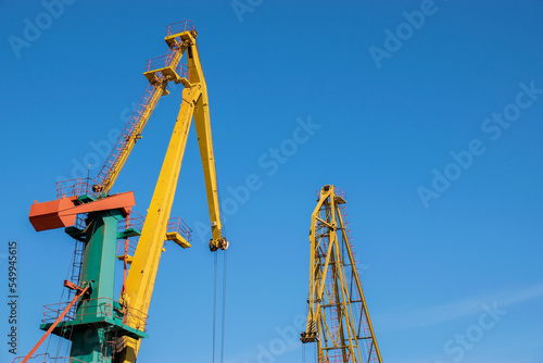 Two port cranes over blue sky background.