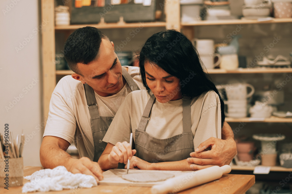 A young couple works in a pottery workshop. The concept of hobbies, lifestyle and relationships. A young couple works in a pottery workshop. The concept of hobbies, lifestyle and relationships.