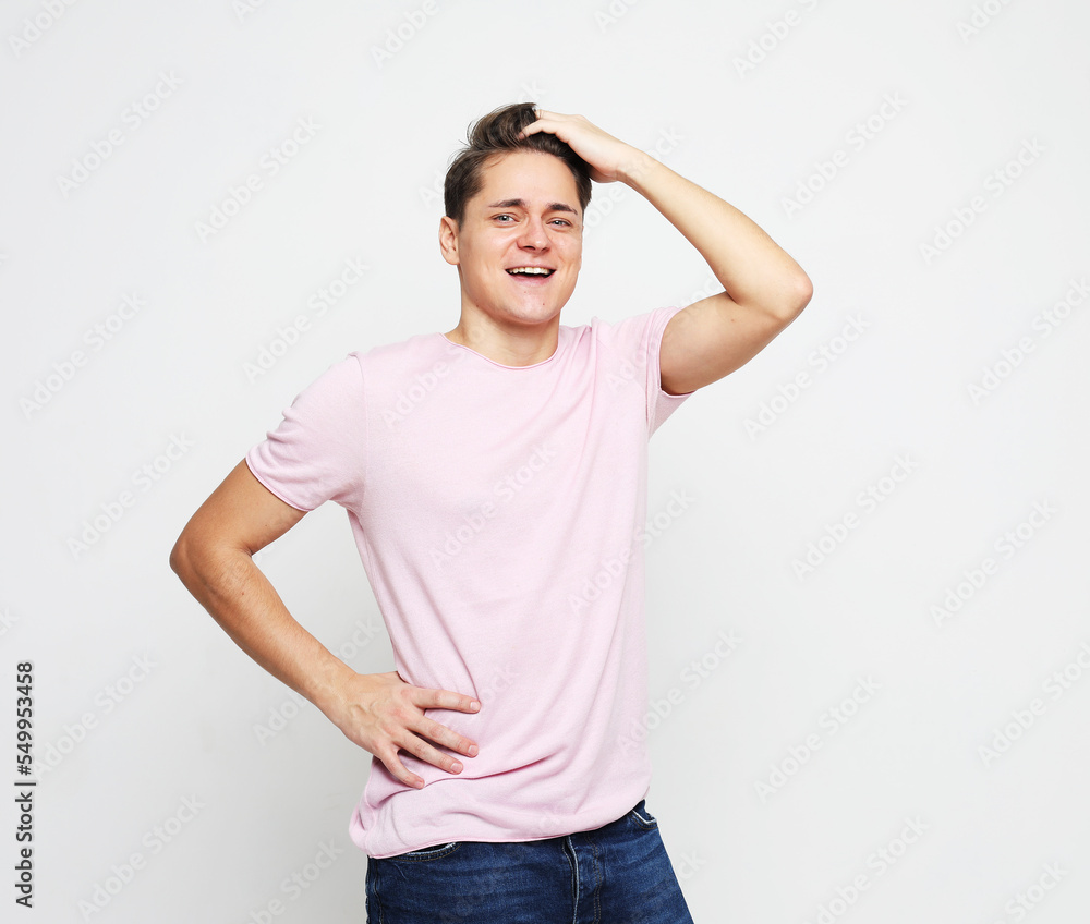 Handsome man in a pink t-shirt touches his hair, straightens his hairstyle