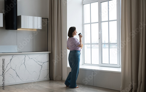 Wallpaper Mural Indoor image of cute curvaceous young brunette woman having cup of coffee in kitchen, near window. Torontodigital.ca