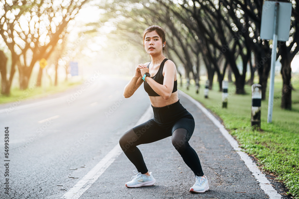 Beautiful fitness asian woman doing squat sit up exercise workout at sport stadium. Attractive female warming up body training wearing sportswear. Healthy and active lifestyle concept.