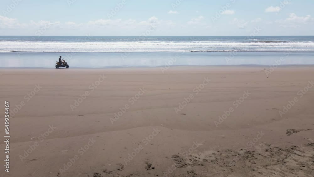 Aerial jib up as ATV crosses frame on beach. Ocean waves crashes on shore. Aerial jib up as ATV crosses frame on beach. Ocean waves crashes on shore.