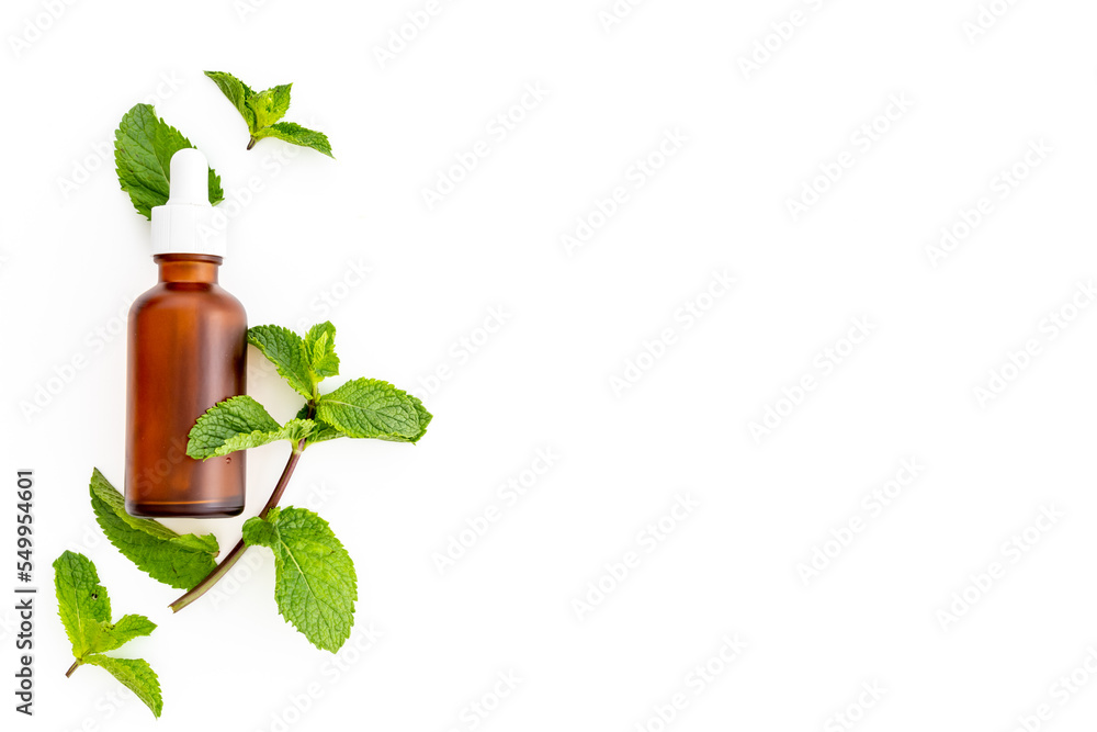Green mint leaves with bottle of essential peppermint oil Green mint leaves with bottle of essential peppermint oil