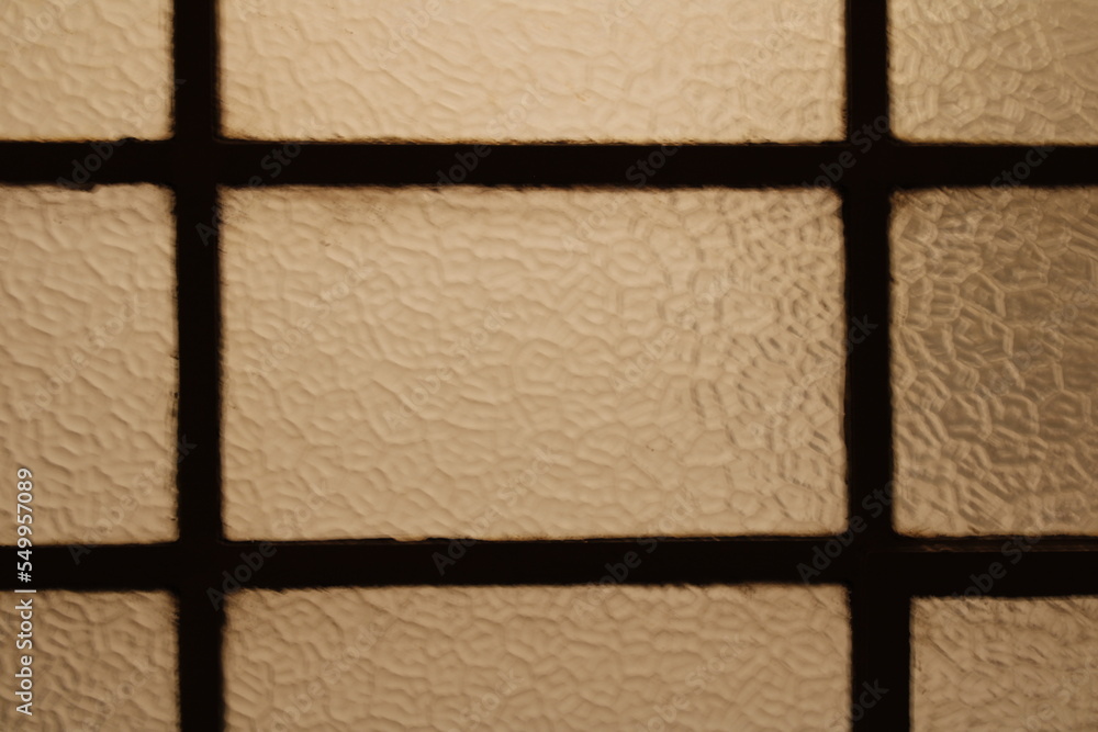 Fototapeta premium Ventanal de hierro forjado antiguo en la sala de la casa con vidrios texturizados tipo Inglès, forma un original diseño abstracto en rectàngulos para fondos