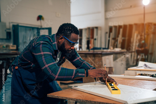 Afro american craftsman working as carpenter in a carpentry workshop, Small family business concept of young entrepreneurs.