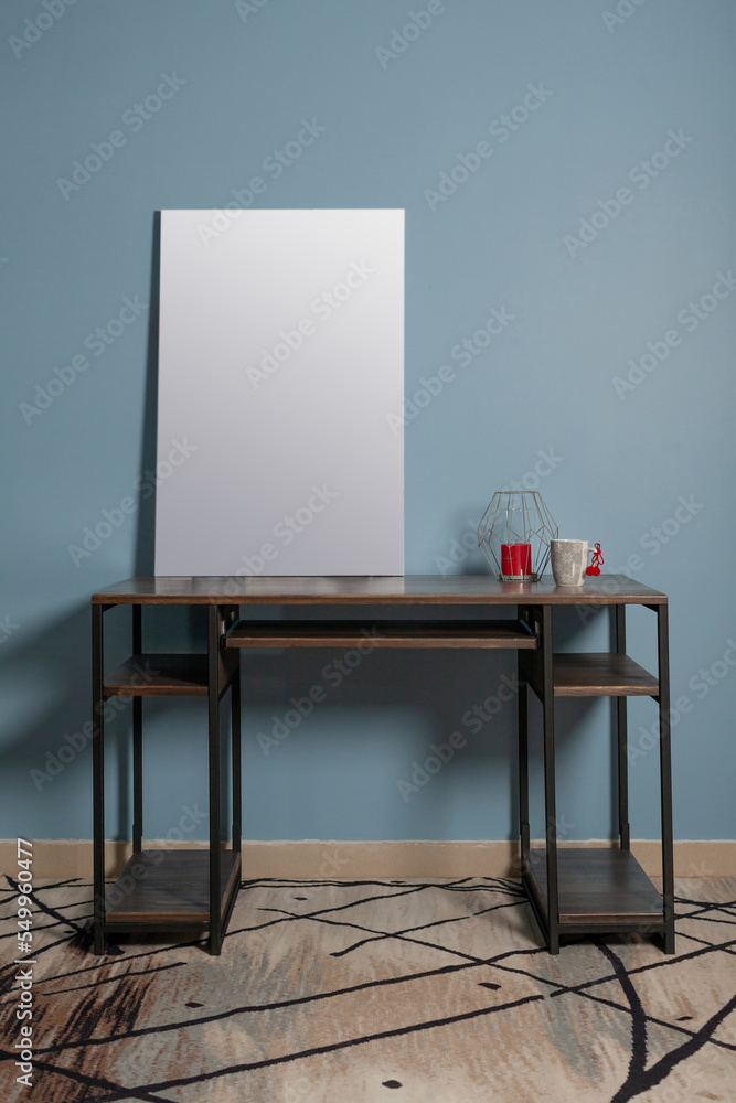 White canvas for painting on a wooden table against a blue wall in the interior mocap White canvas for painting on a wooden table against a blue wall in the interior mocap