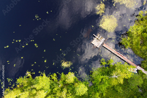 Lake for fishing with wooden pier, aerial view. Mole (pier) on the lake. Aerial landscape, summer lake shore with dock for boats