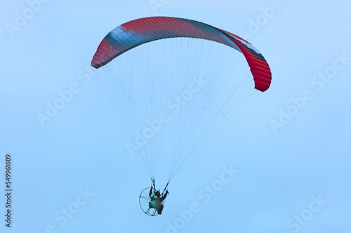 Paraglider flying on the blue sky background