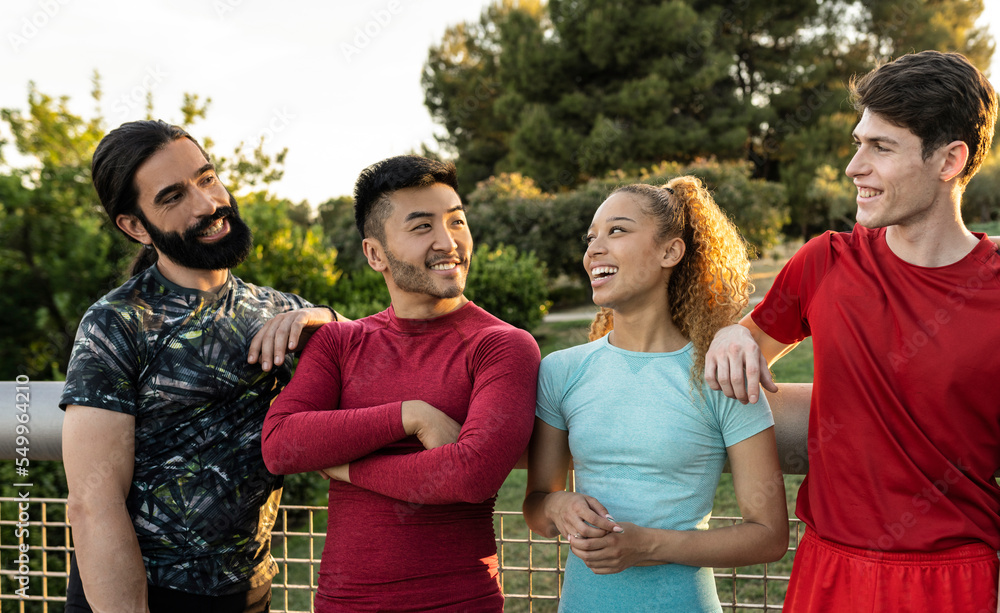 Group of four multiracial athletes looking at each other. Focus on the Asian man with his arms crossed.