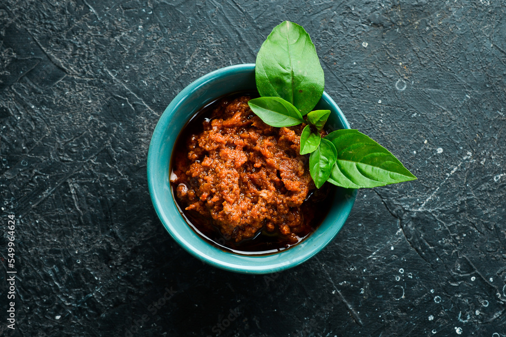 Pesto sauce with sun-dried tomatoes in a bowl. Traditional Italian sauce. On a concrete background. Pesto sauce with sun-dried tomatoes in a bowl. Traditional Italian sauce. On a concrete background.