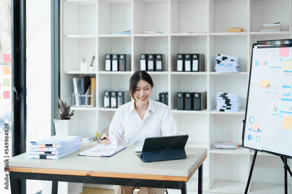 Portrait of a woman business owner showing a happy smiling face as he has successfully invested her business using computers and financial budget documents at work Portrait of a woman business owner showing a happy smiling face as he has successfully invested her business using computers and financial budget documents at work