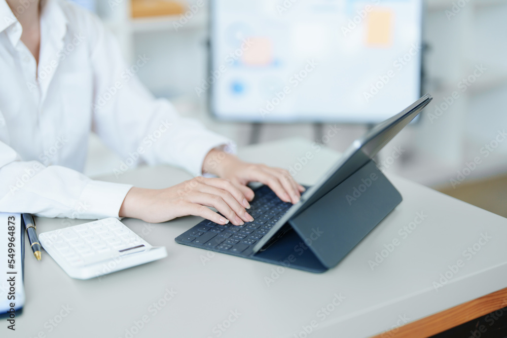 Portrait of a thoughtful Asian businesswoman looking at financial statements and making marketing plans using a computer on her desk Portrait of a thoughtful Asian businesswoman looking at financial statements and making marketing plans using a computer on her desk
