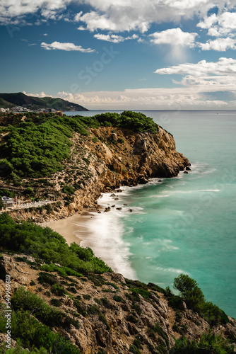 Nice cliff in the mediterranean sea near Sitges and Vilanova i la Geltru, spain. Long exposure photography on a sunny day overlooking the dead man's beach, vertical photo