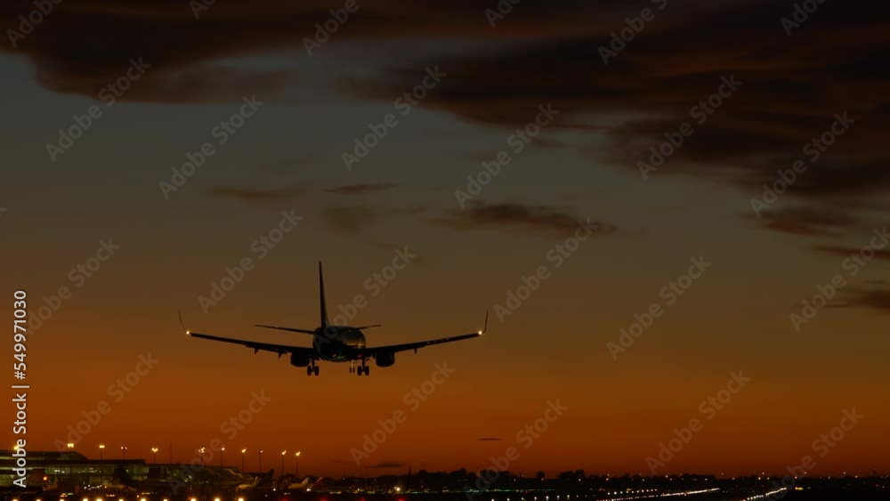 Tracking shot of airplane landing at airport during cinematic twilight Tracking shot of airplane landing at airport during cinematic twilight