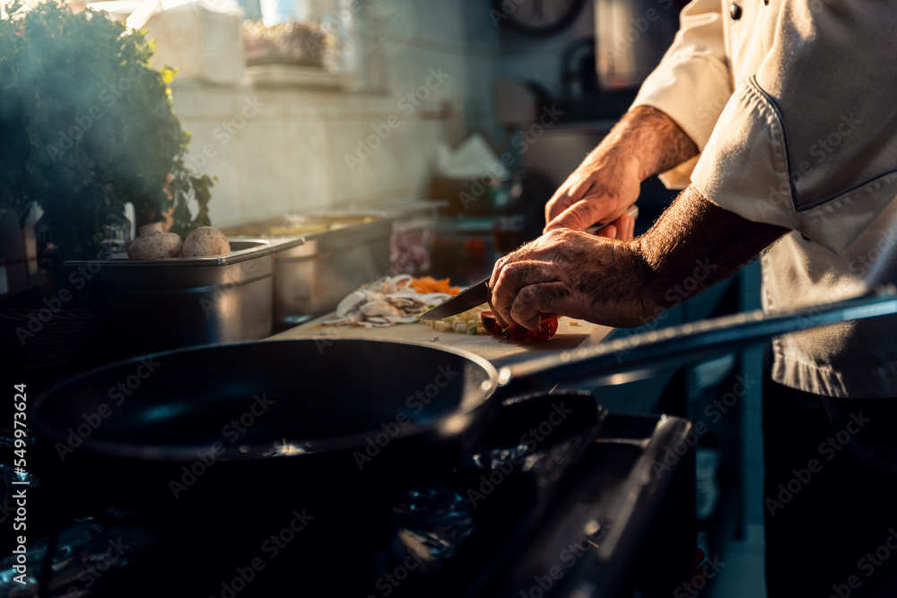 Chef cooking in a commercial kitchen choping vegetable. Chef cooking in a commercial kitchen choping vegetable.