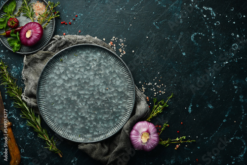 Dark kitchen table with spices and kitchen utensils. On a black stone background.