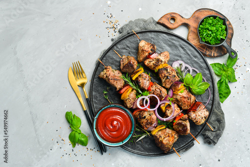 Traditional Kebab. Juicy pork skewers with vegetables on a black stone plate. Barbecue. Top view. Free space for text.