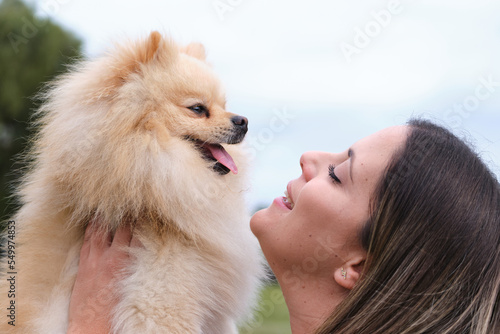 Close up of girl looking lovingly at her pomeranian breed dog