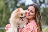 Portrait of a girl posing with her pomeranian dog in a park.