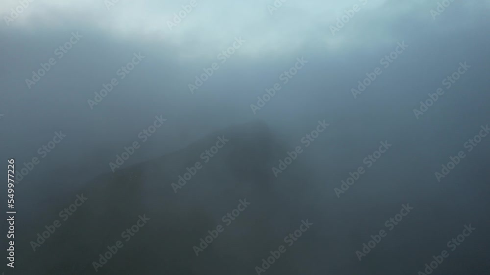 Flying through clouds and revealing mountain in gloomy weather. English countryside landscape on a stormy cloudy afternoon. Peak District National Park in thick fog and clouds, drone footage 4k, 30fps Flying through clouds and revealing mountain in gloomy weather. English countryside landscape on a stormy cloudy afternoon. Peak District National Park in thick fog and clouds, drone footage 4k, 30fps