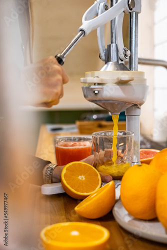 Closeup woman hand holding glass under flow of detox healthy orange juice use citrus press