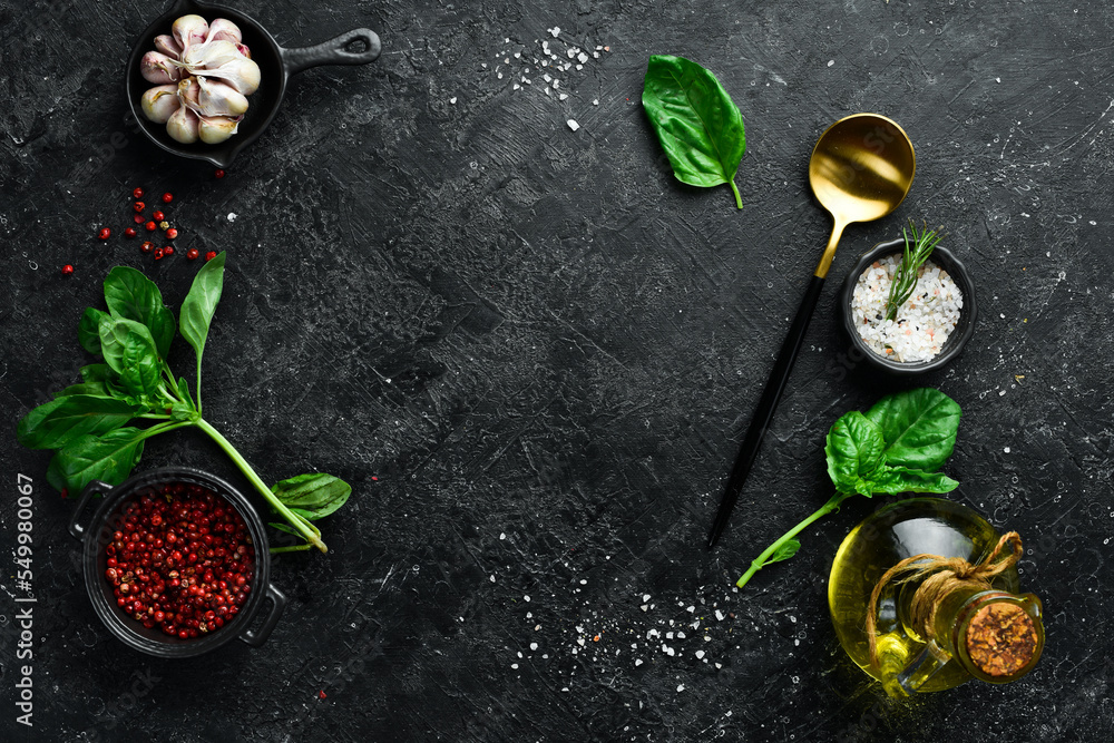 Cooking background: cutlery, spices and basil. On a black stone background. Cooking background: cutlery, spices and basil. On a black stone background.