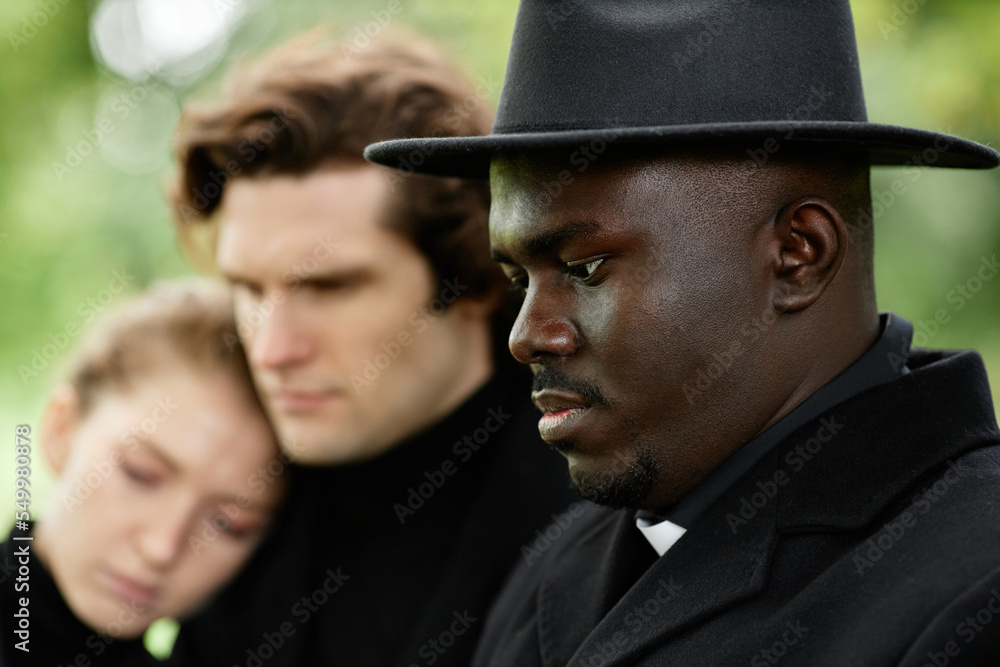 Side view portrait of African American priest holding ceremony at outdoor funeral Side view portrait of African American priest holding ceremony at outdoor funeral
