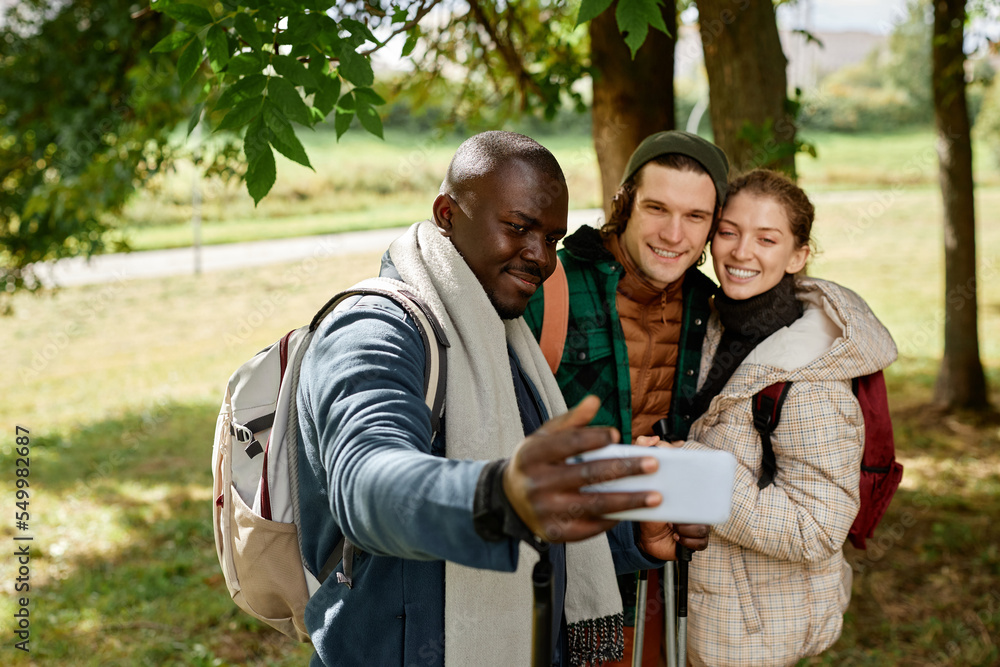 Group of smiling friends taking selfie photo in nature while enjoying hike together Group of smiling friends taking selfie photo in nature while enjoying hike together