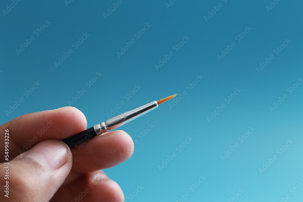a close up of a hand holding a painting brush a close up of a hand holding a painting brush