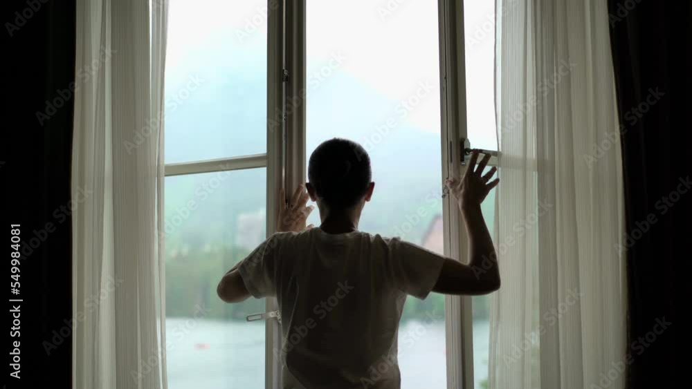 Girl opens the curtains in the morning with arms stretched Girl opens the curtains in the morning with arms stretched