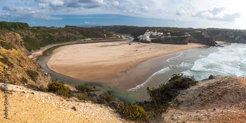 Panoramic view of Praia de Odeceixe Mar Surfer beach with golden sand, atlantic ocean waves, river bend and white houses of Odeceixe village. Rota Vicentina coast, Odemira, Portugal. photo