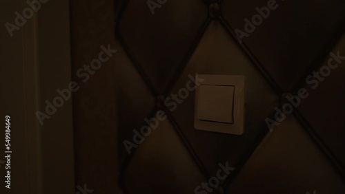 energy savings. Hand turns off the light switch.