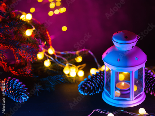 Christmas lantern on a festive decorated table. Vintage garland and neon background lighting