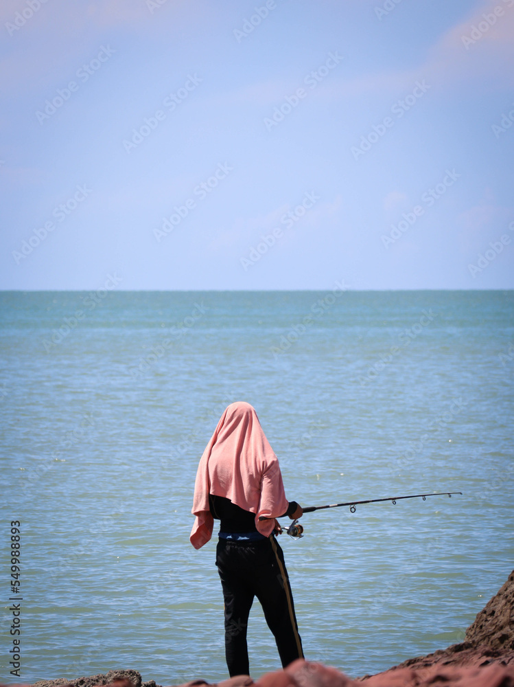 man fishing at rocky beach on sunny day man fishing at rocky beach on sunny day