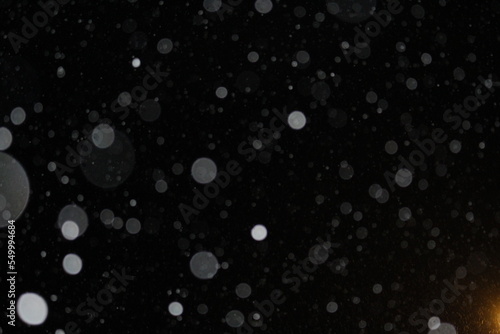 Abstract winter snowflakes idea bokeh effect on black background, Snow falling concept with glowing light at bottom right. Abstract christmas winter background