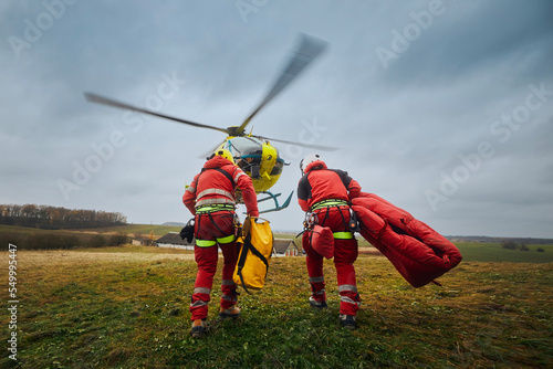 Two paramedic with safety harness and climbing equipment running to helicopter emergency medical service. Themes rescue, help and hope. ..
