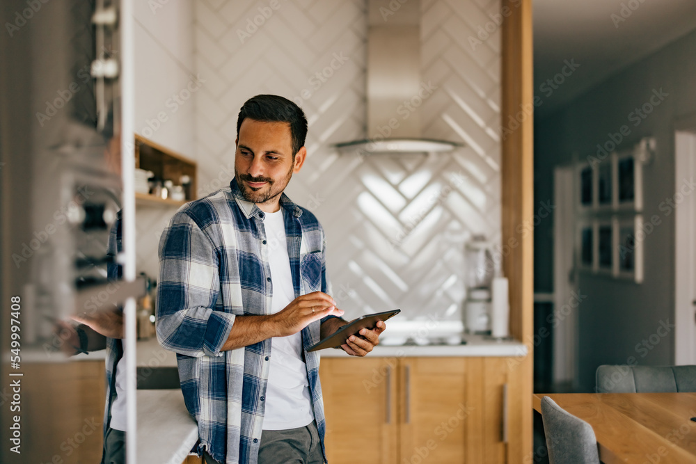 An adult man, looking on the side while standing in the kitchen An adult man, looking on the side while standing in the kitchen