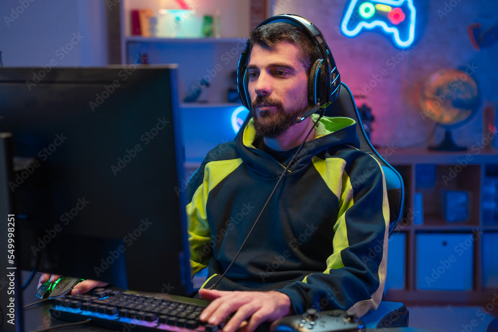 Naklejka premium Male gamer focusing on online video games championship, playing action game on online live stream. Caucasian player having fun with virtual esport gameplay tournament on computer. High quality photo