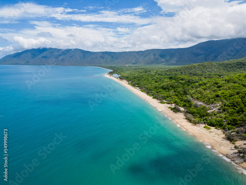 Aerial view of tropical beach, lush rainforrest, mountains and ocean.