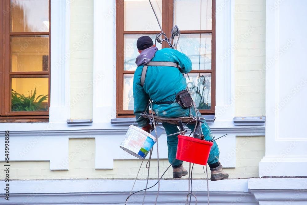 climber worker maintains a window and facade of a residential building in repair. construction business industry climber worker maintains a window and facade of a residential building in repair. construction business industry