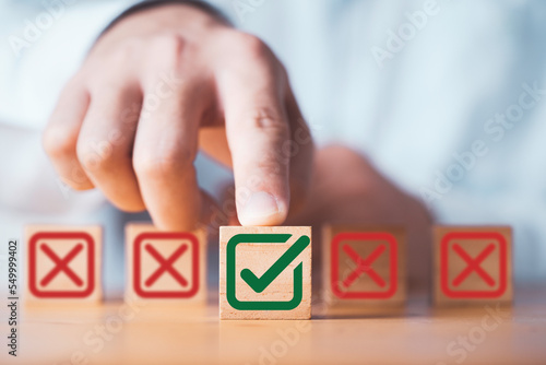 Schilderij op canvas Businessman Pushing green correct sign mark between Red Cross mark which print screen on wooden cube block for approve and reject business project proposal concept