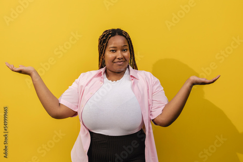 Smiling woman gesturing in front of yellow wall