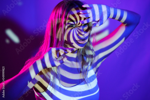 Young woman with illuminated swirl pattern in front of wall photo