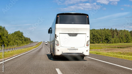 New modern passenger bus on the road in summer against the blue sky. The concept of passenger transportation and traveling around the countries by bus. Copy space for text