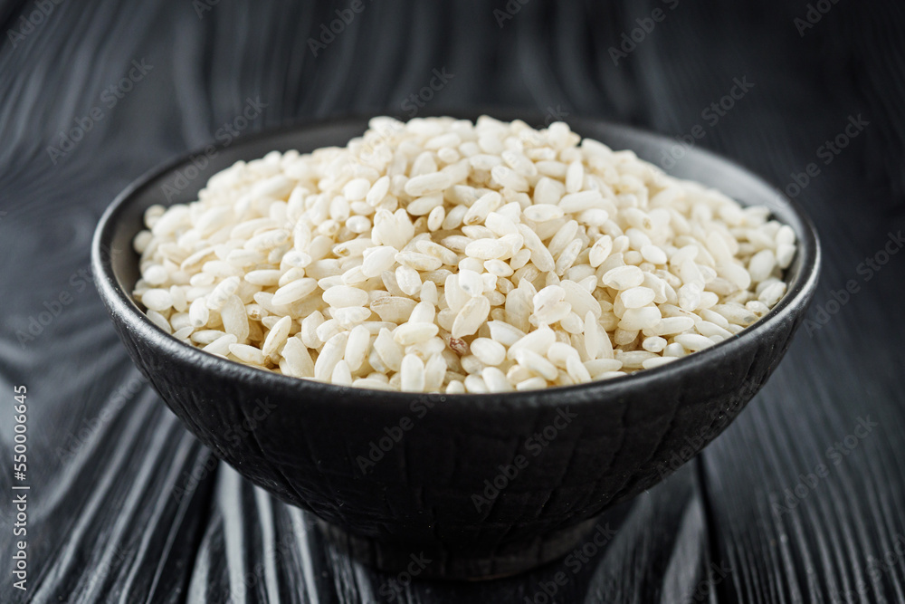 arborio rice for risotto on a black wooden background arborio rice for risotto on a black wooden background