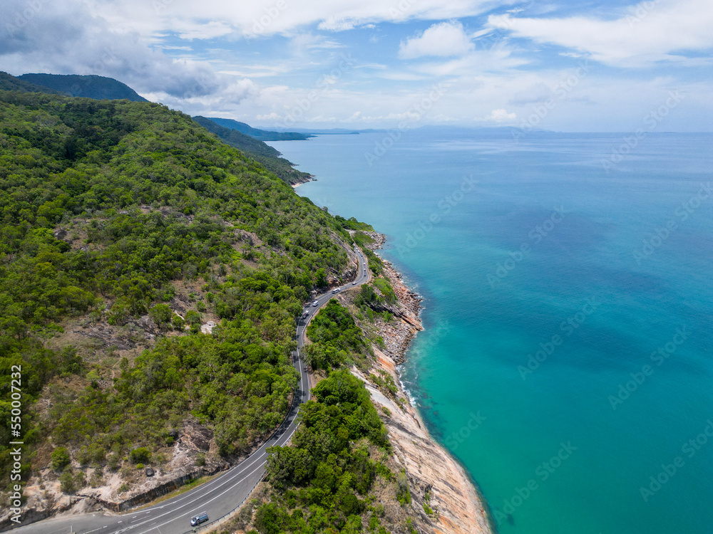 Aerial view of tropical winding road following blue ocean and rainforrest Aerial view of tropical winding road following blue ocean and rainforrest