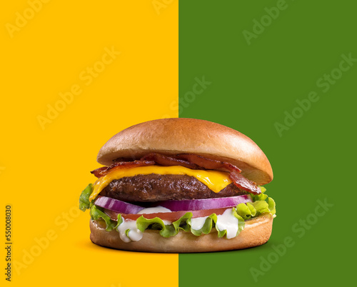 Fresh tasty burger on green and yellow background. cheese beef burger consists of bun bread  lettuce  tomato  onion  mayonnaise  and cheddar cheese